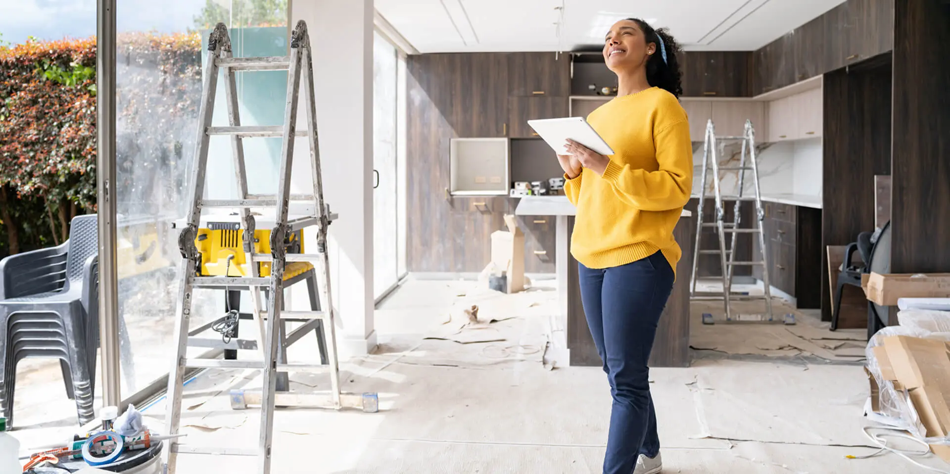 Woman inspecting kitchen renovation with tablet.