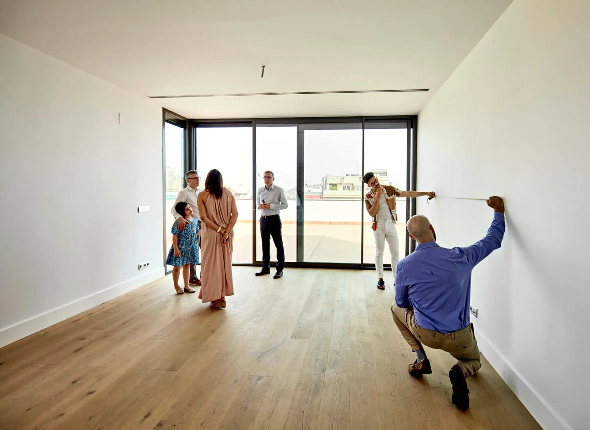 Family viewing empty room with measuring tape.