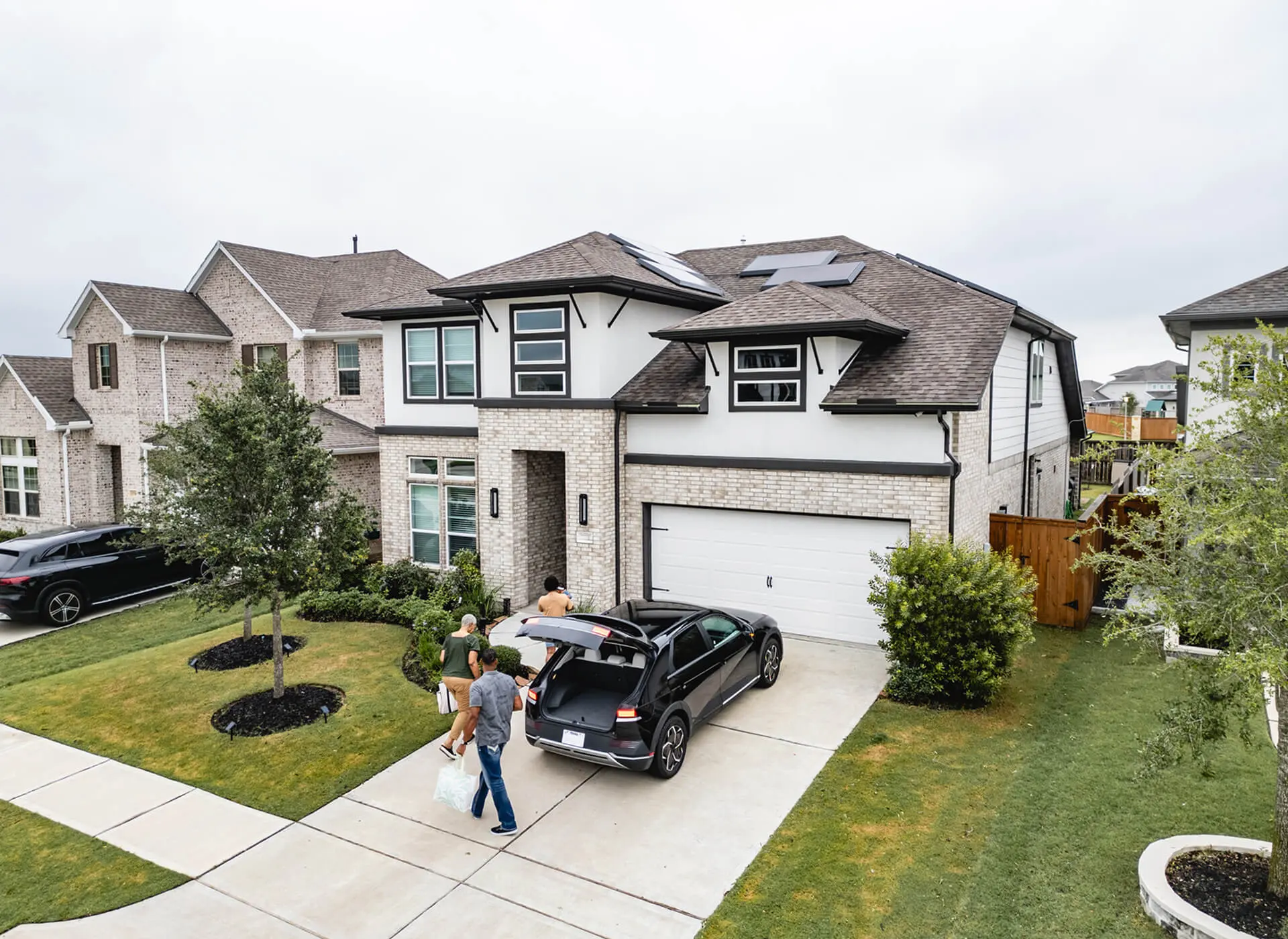 Family unloading car at suburban house.